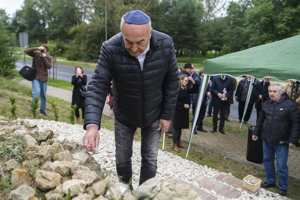 Zygmunt Stępiński, dyrektor Muzeum POLIN, kładzie kamyk przy tablicy upamiętniającej cmentarz żydowski w Janowie Lubelskim.