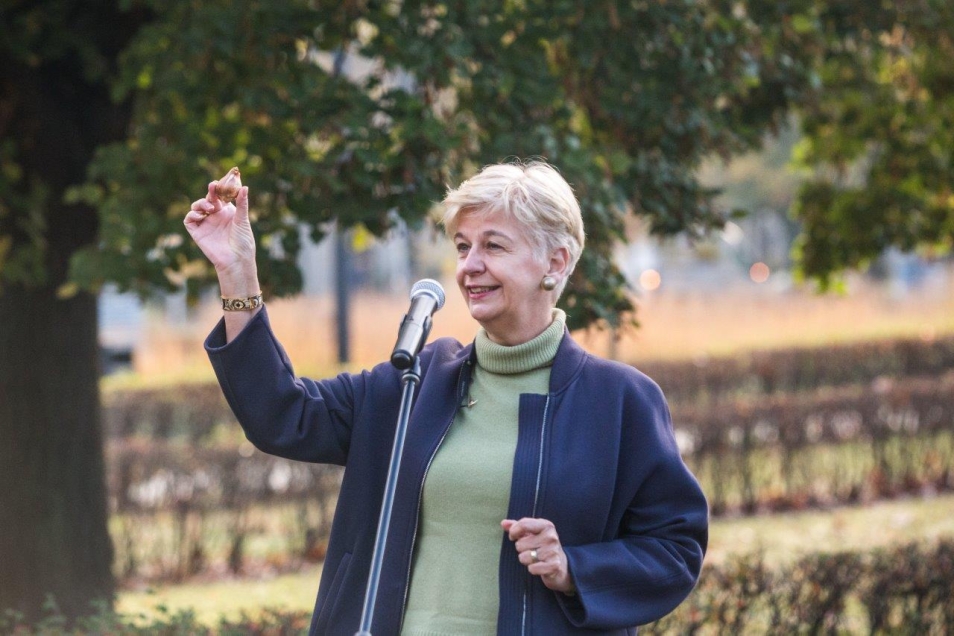 Ambasador Królestwa Niderlandów w Polsce Daphne Bergsma trzyma cebulkę tulipana i stoi przy mikrofonie.