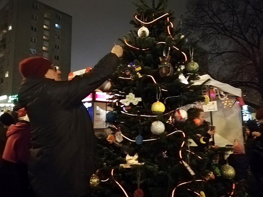 Mieszkanka Muranowa ubiera choinkę stojącą na osiedlu.