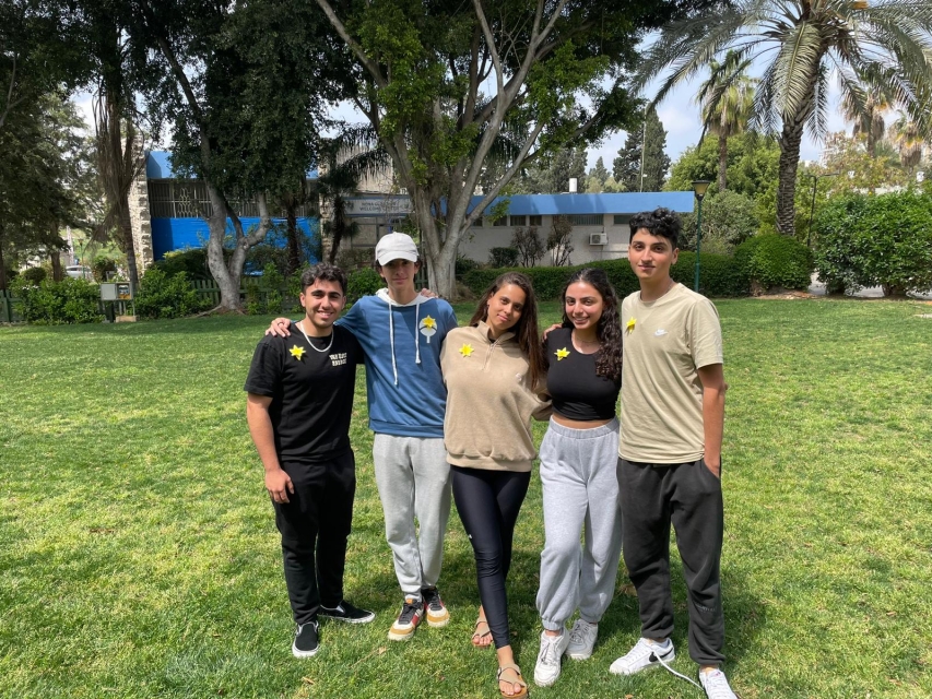 Five young people from Israel with paper daffodils on their clothes.