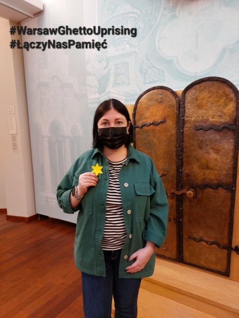 The 2022 Warsaw Ghetto Uprising Campaign in Lithuania. A woman is standing and holding paper daffodil in her hand. She is also wearing face mask.