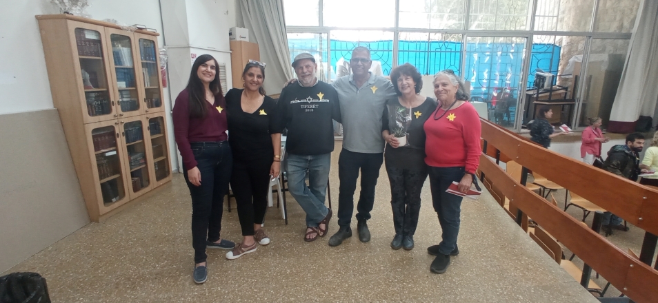 Six teachers from Israel standing next to each other in a class. They have paper daffodils pinned to their clothes. 