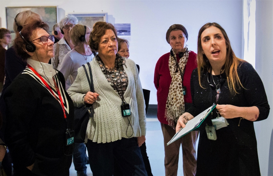 rzewodniczka Muzeum POLIN Katarzyna Jankowska stoi na wystawie z grupą seniorów.
