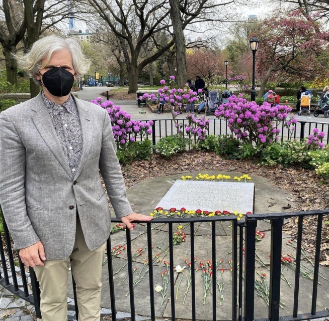 Simon from NY standing next to metal fence. Behind there is some commemorative plaque.