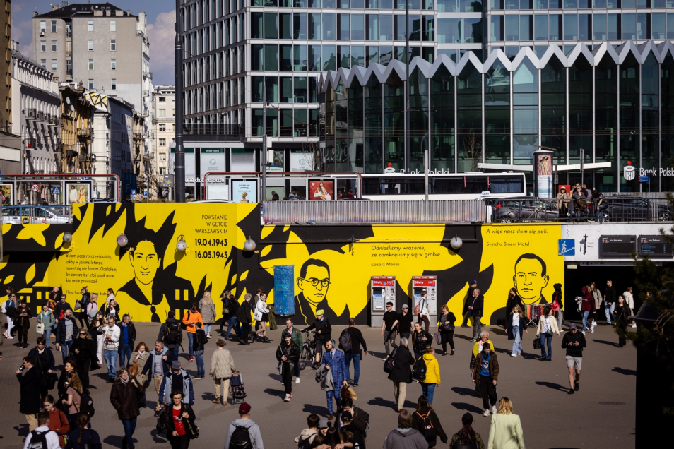 Tłum ludzi przy metrze Centrum w Warszawie. Na ścianach wokół tzw. patelni mural przedstawiający cywilów z getta warszawskiego.