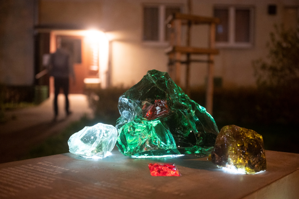 Na postumencie przymocowane kolorowe świecące kamienie - symbolizujące kryjówki w getcie warszawskim.