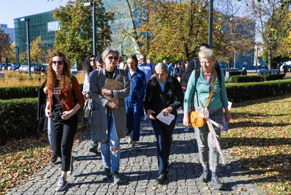 Grupa seniorów idzie alejką przy Muzeum POLIN.