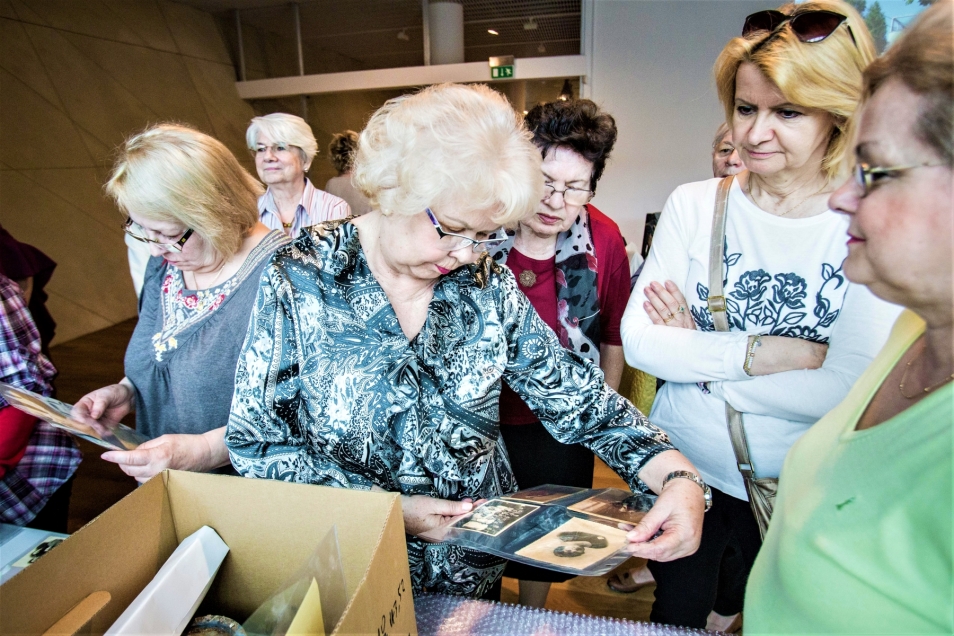 Seniorki oglądają zdjęcia podczas spotkania.