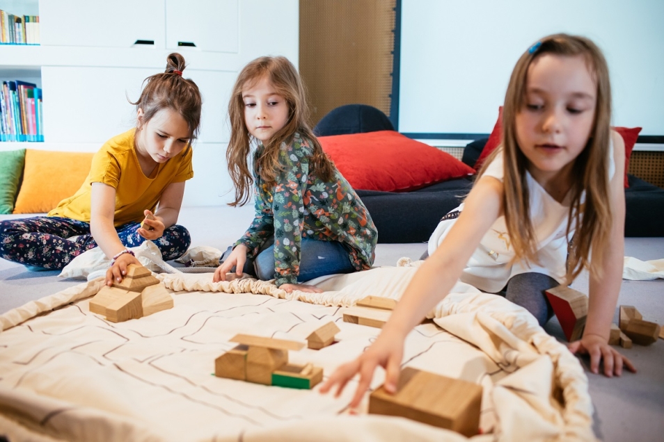 Trzy dziewczynki bawią się klockami w Miejscu edukacji rodzinnej w Muzeum POLIN.
