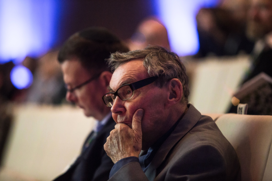 Zamyślony Marian Turski siedzi z dłonią opartą o podbródek podczas kongresu Żydowskie Dziedzictwo Kulturowe.