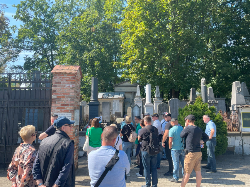 Grupa stoi przed bramą cmentarza podczas spaceru w ramach projektu BETAAEC.