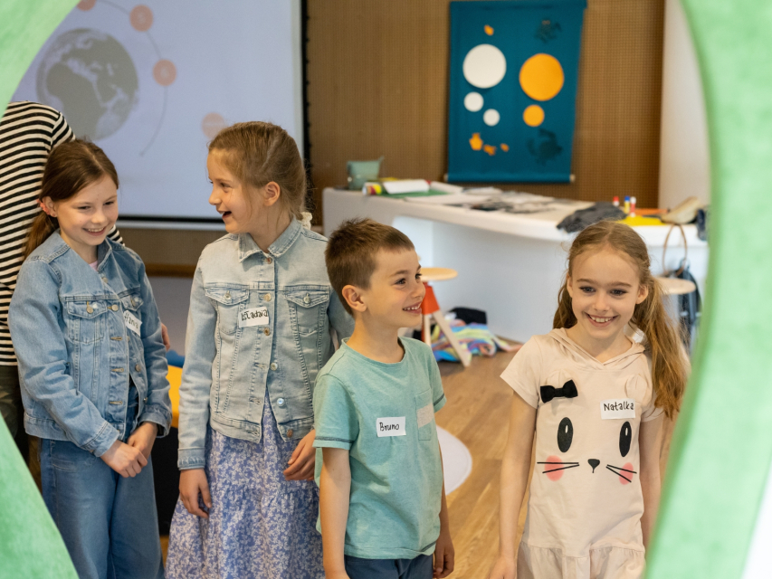 Czworo uśmiechniętych dzieci stoi w Miejscu edukacji rodzinnej w Muzeum POLIN.