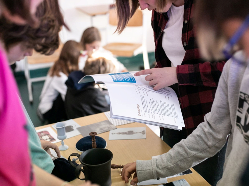 Dzieci oglądają obiekty i czytają karty do gry "Muzeum w pudełku".