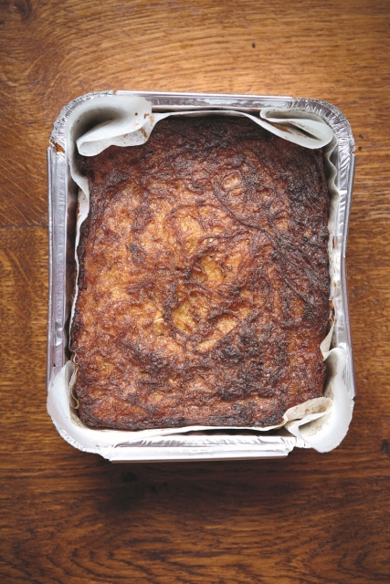 Kugel ziemniaczany stoi w blaszce na stole.