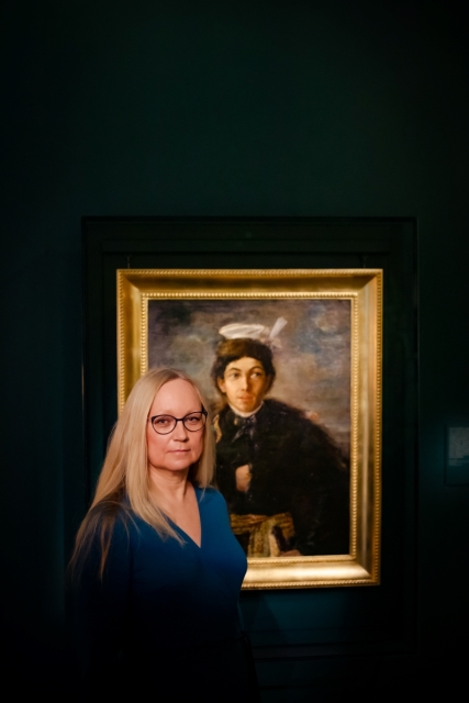 Beata Meller stoi przy obrazie "Autoportret w stroju polskiego szlachcica" Maurycego Gottlieba.