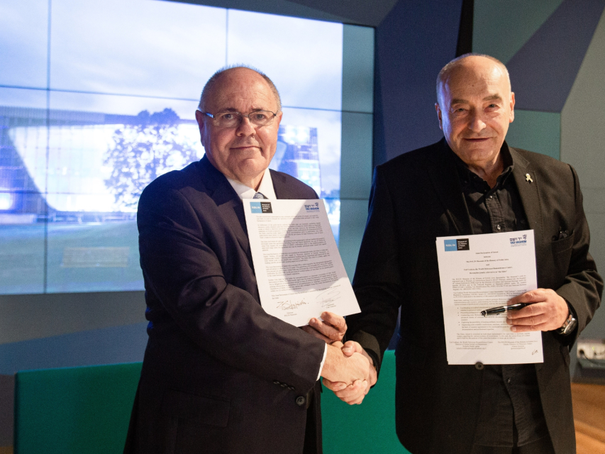 Przewodniczący Jad Waszem, Dani Dayan, oraz dyrektor Muzeum POLIN, Zygmunt Stępiński ściskają sobie dłoń. W drugiej ręce trzymają podpisaną umowę o współpracy.