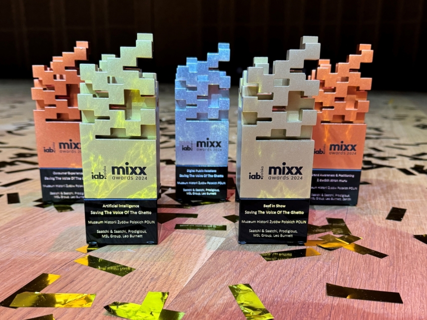 Pięć statuetek MIXX Awards 2024 stoi obok siebie na scenie udekorowanej konfetti.