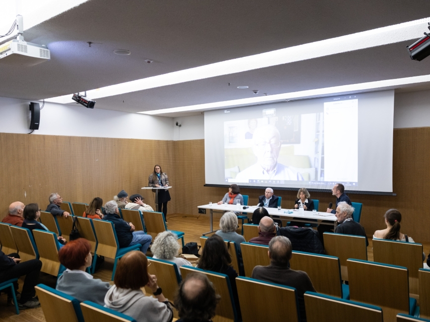 Uczestniczki i uczestnicy spotkania z autorkami i autorami czasopisma "Plotkies" siedzą w sali konferencyjnej.