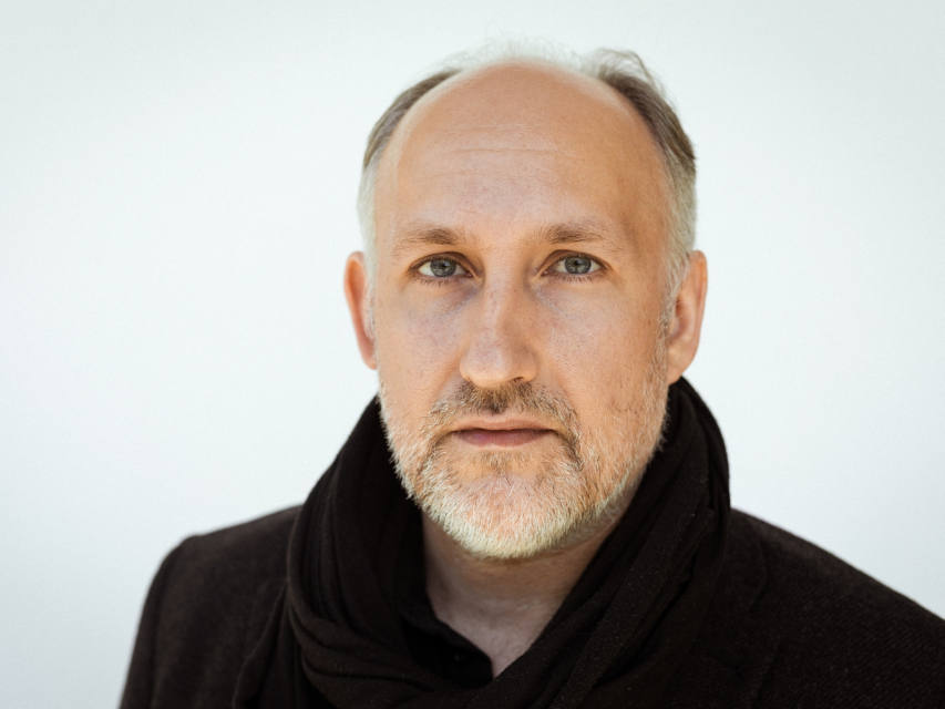Józef Markiewicz - mężczyzna w średnim wieku, z siwą brodą, ubrany w czarny płaszcz. 
