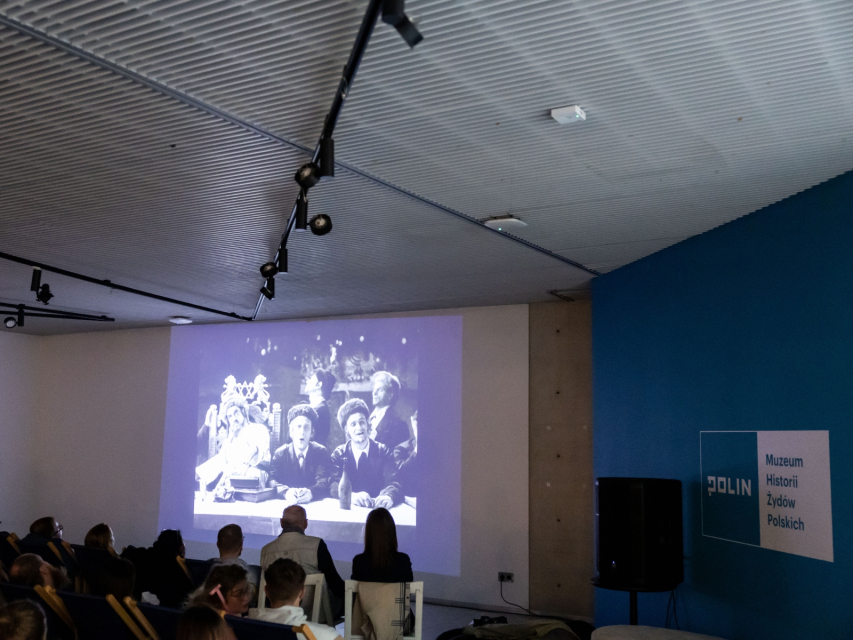 Grupa osób ogląda film w galerii "Dziedzictwo" Muzeum POLIN.