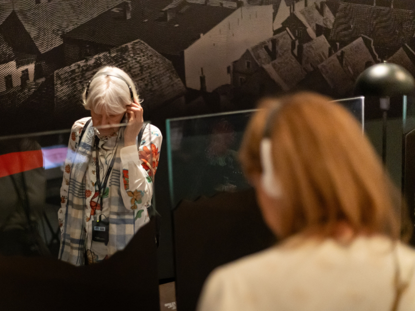 Dwie kobiety zwiedzają w słuchawkach wystawę "1945. Nie koniec, nie początek".