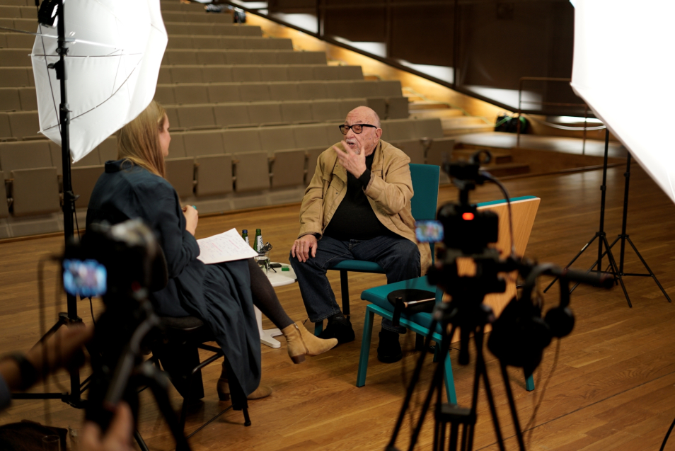 Jerzy Hoffman talks to Joanna Król-Komła. An empty auditorium in the background.