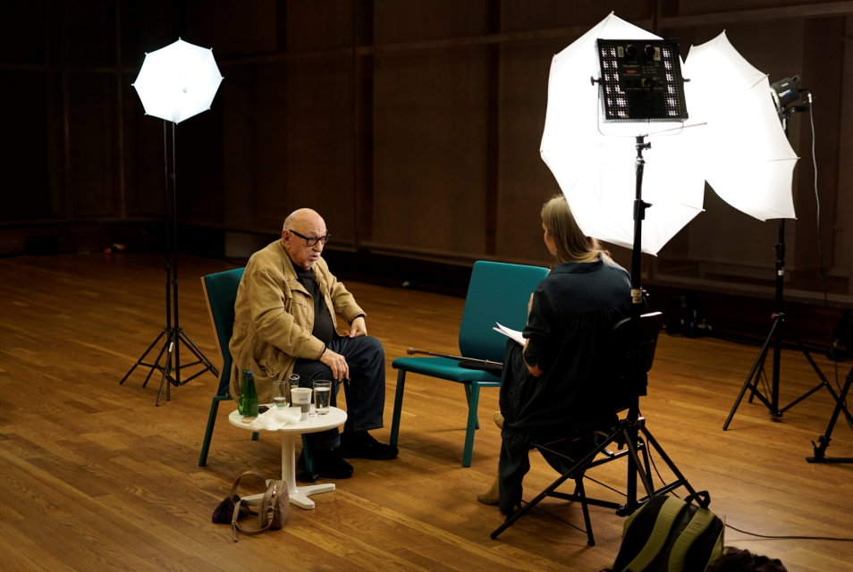 Recording of an oral history interview with Jerzy Hoffman – Joanna Król-Komła is sitting opposite the director. Lighting is set up around them.