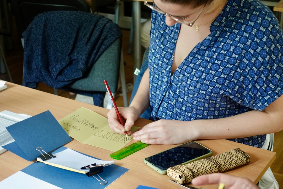 Kobieta pisze litery na kartce podczas seminarium języka i kultury jidysz.