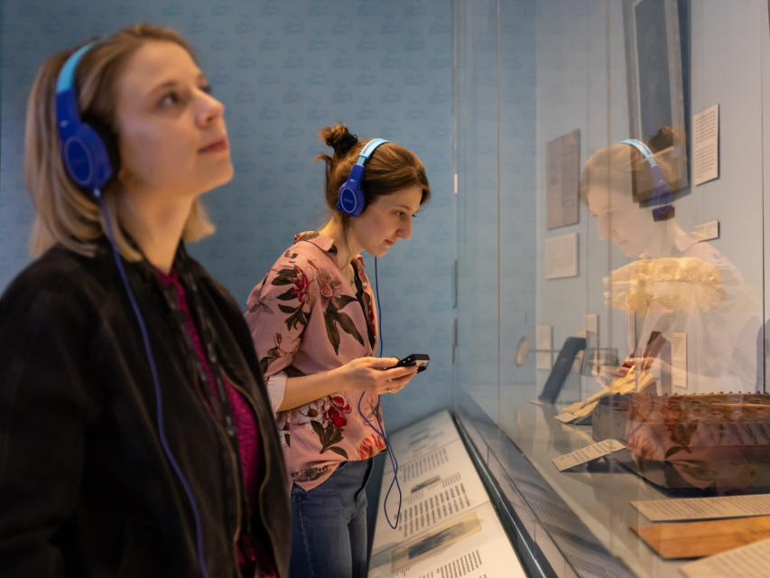 Dwie kobiety w słuchawkach na uszach zwiedzają wystawę stałą w Muzeum POLIN.