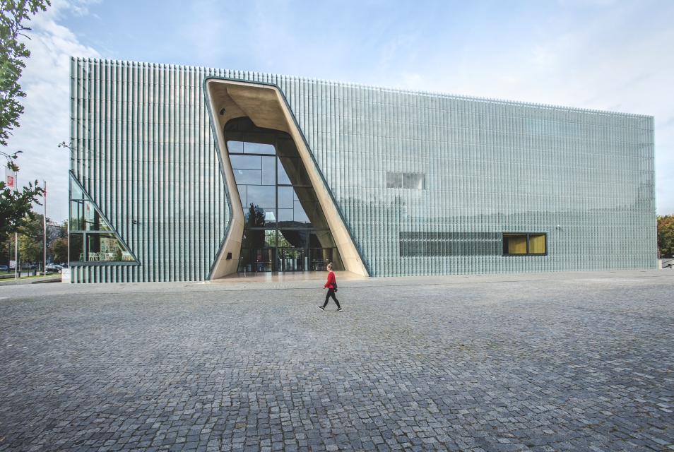 POLIN Museum building on Bohaterów Getta Square. A man walks by it.