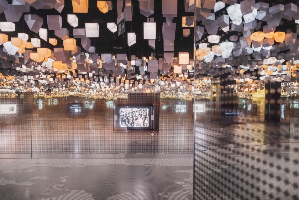 Hanging houses on the ceiling in the Bonds gallery. A film is playing on a screen in the background