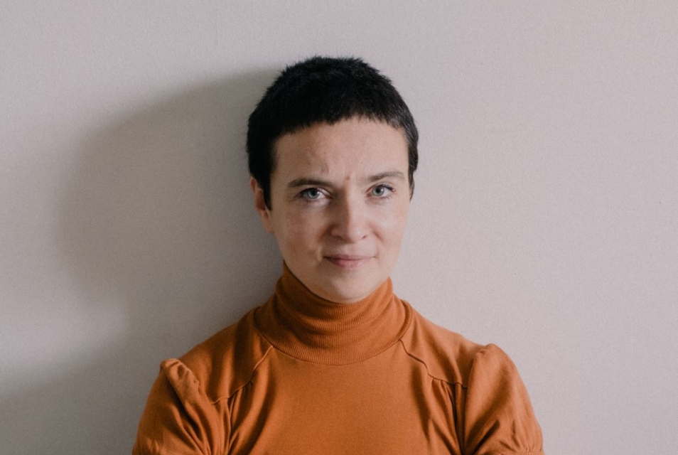 Patrycja Dolowy sits on the floor, holding her clasped hands in front of her.