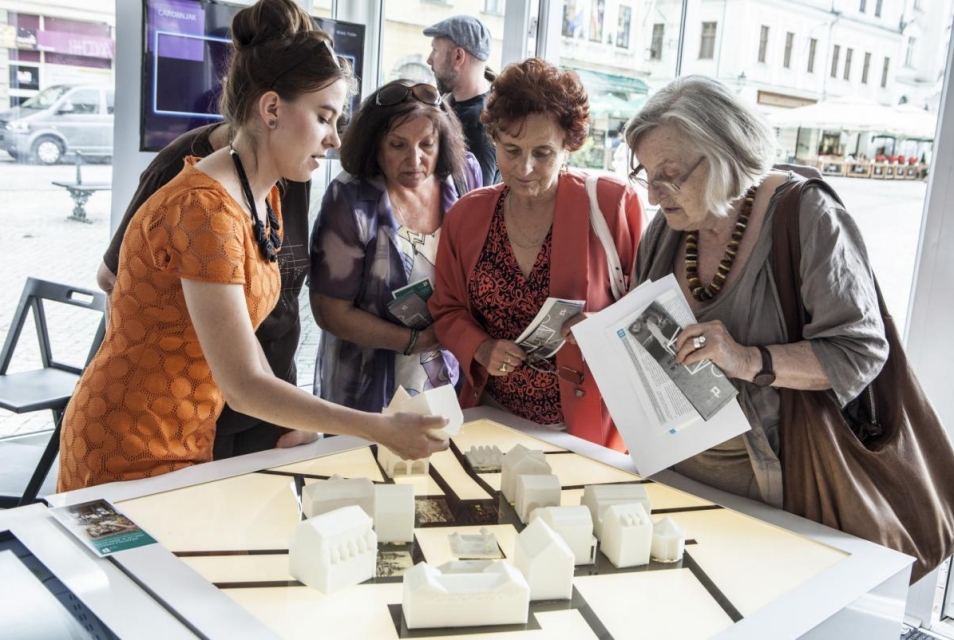 Seniorki oglądają z edukatorką makietę na wystawie "Muzeum na kółkach".