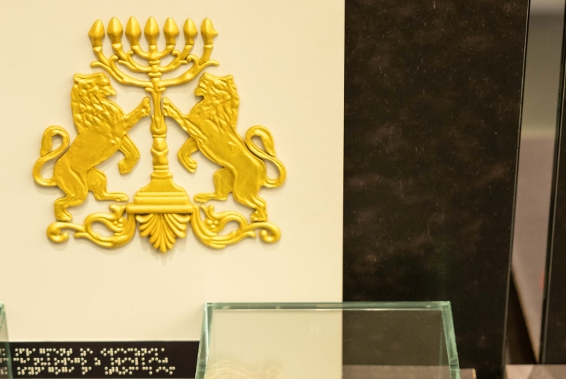 Tyflografika z motywem złotego świecznika i lwów po obu jego stronach.