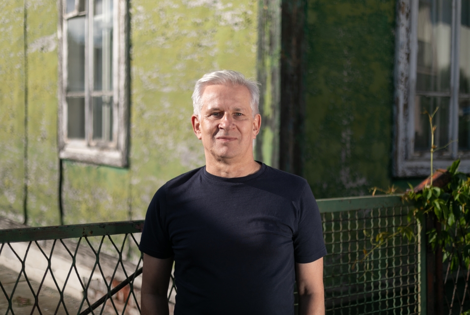 Marek Kołcon przed drewnianym budynkiem w Zamościu