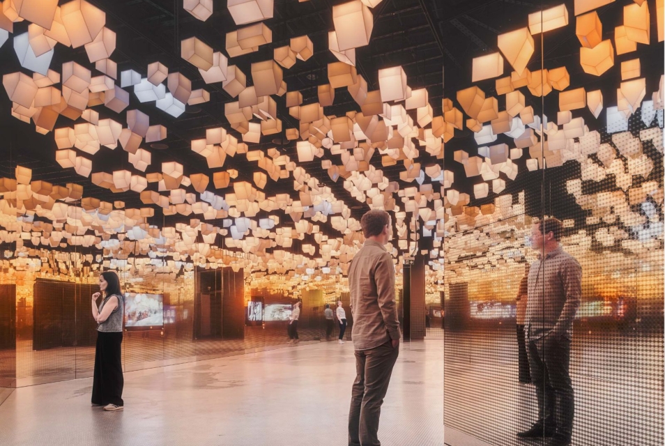 There are two people standing in the “Więzi” gallery. Their silhouettes are reflected in the mirrors on the gallery walls.