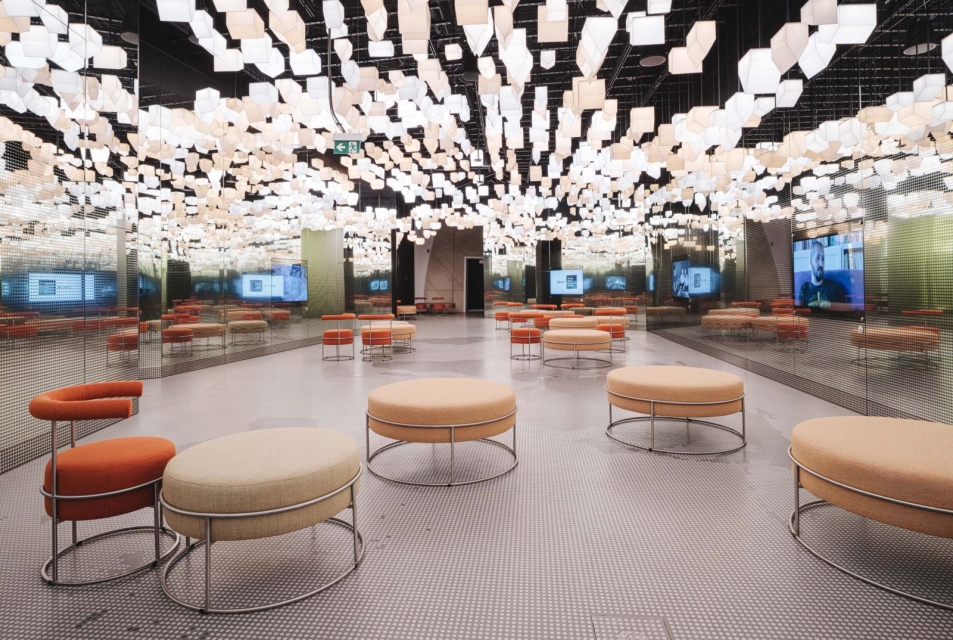The interior features numerous poufs for seating, and numerous small lanterns in the shape of houses hang from the ceiling, practically forming the ceiling.