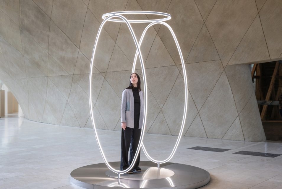 A woman stands inside the light installation ‘Echo’ in the main hall of POLIN Museum.