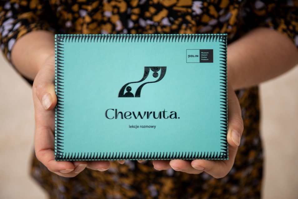 Ktoś trzyma przed sobą pudełko z kartami do gry "Chewruta. Lekcje rozmowy".