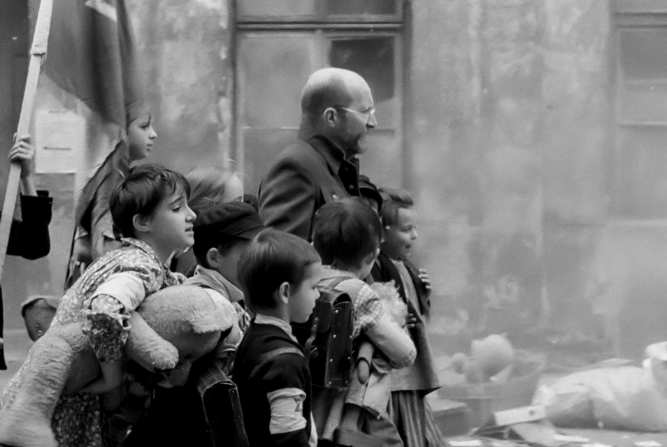 Czarno-biały kadr z filmu "Korczak". Grupa dzieci stoi obok Janusza Korczaka.