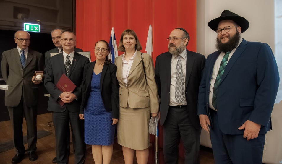 Grupa odświętnie ubranych ludzi stoi w rzędzie.