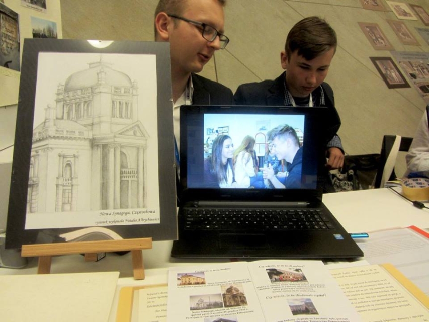 Rysunek budowli, zdjęcie wyświetlone na ekranie laptopa i dwóch mężczyzn.