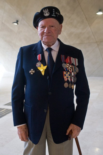 Żołnierz w garniturze, do którego ma przypięte medale i papierowy żonkil.