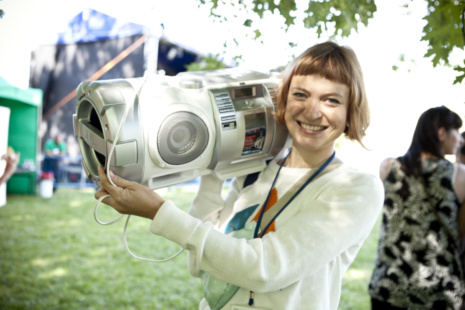 Uśmiechnięta dziewczyna trzyma duże radio na ramieniu.