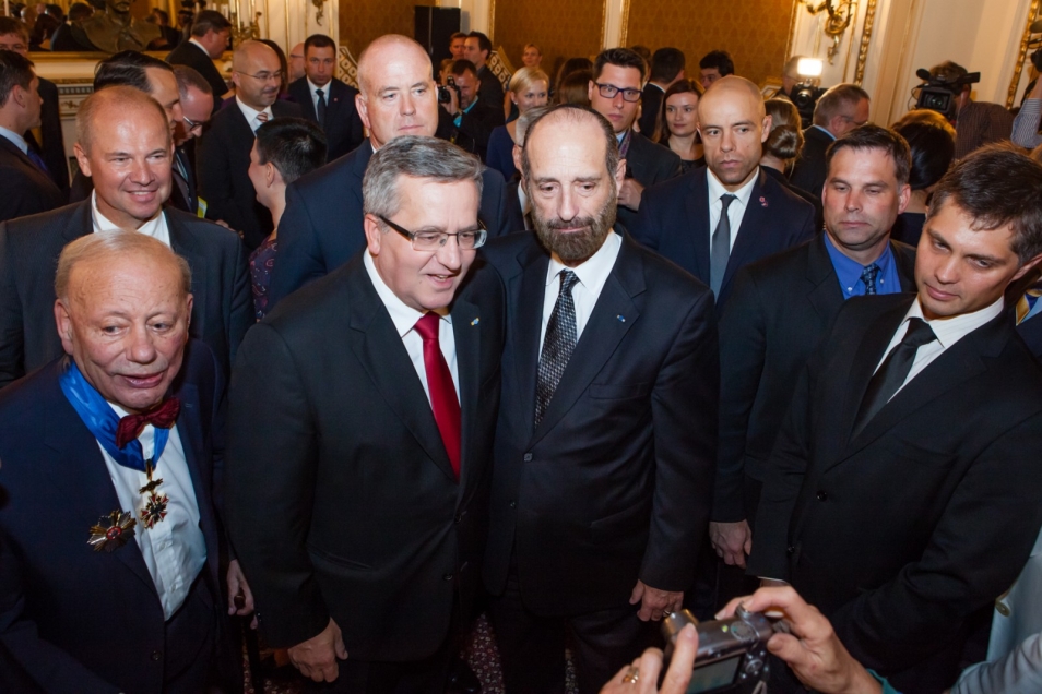 Bronisław Komorowski otoczony przez grupę mężczyzn.