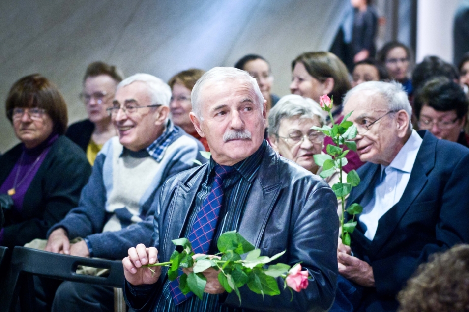 Kilka mężczyzn trzyma róże na wernisażu "Biografie rzeczy" w 2013 r.