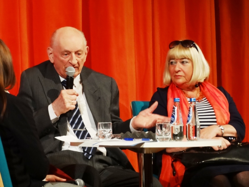 Dwie osoby siedzą przy stole podczas debaty.