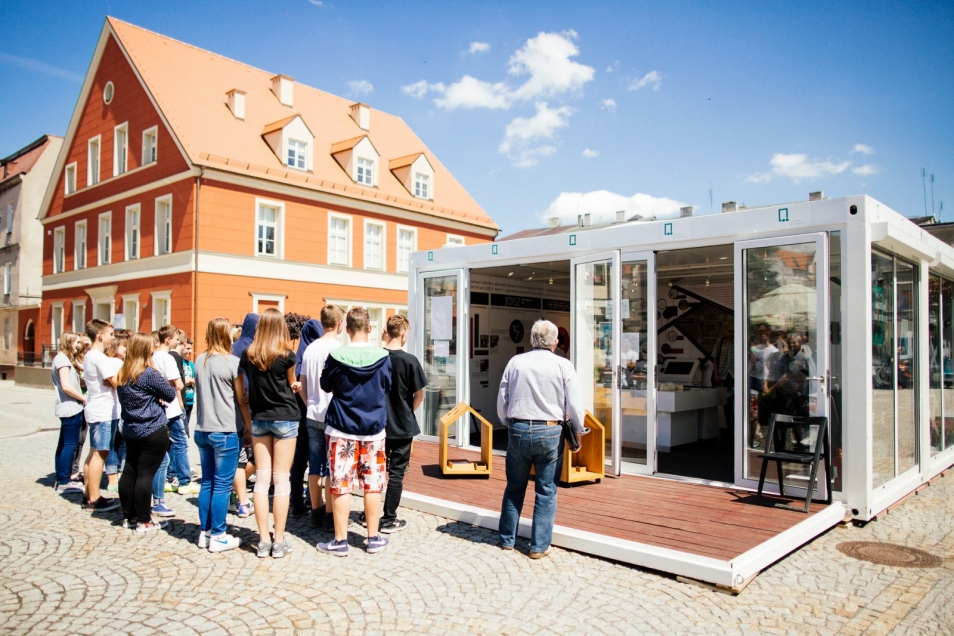Muzeum na kółkach, pawilon ustawiony w miejscowości Kępno. Przed pawilonem grupa zwiedzających.