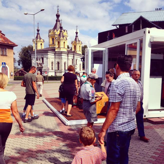 Tomaszów Mazowiecki. Grupa ludzi wokół baraku Muzeum na kółkach.