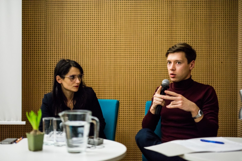 Prezentacja projektu rezydencyjnego. Mężczyzna mówi przez mikrofon, obok siedzi kobieta.